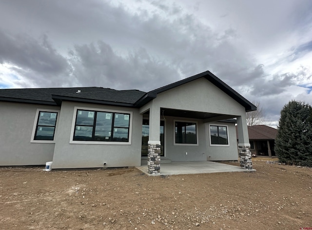 back of house featuring a patio area, roof with shingles, and stucco siding