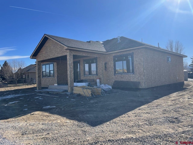 rear view of property featuring covered porch and stucco siding