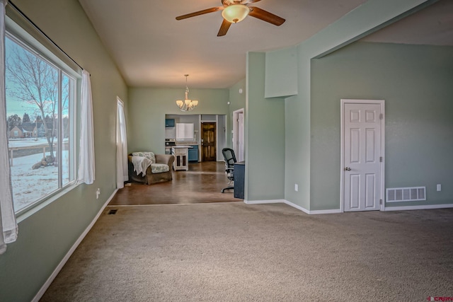 spare room featuring ceiling fan with notable chandelier