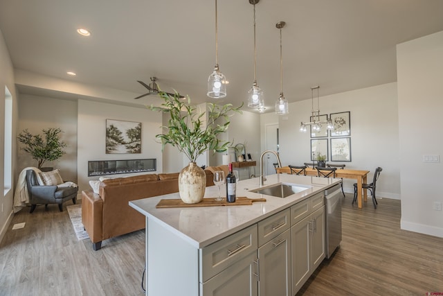 kitchen featuring a kitchen island with sink, sink, decorative light fixtures, and dishwasher