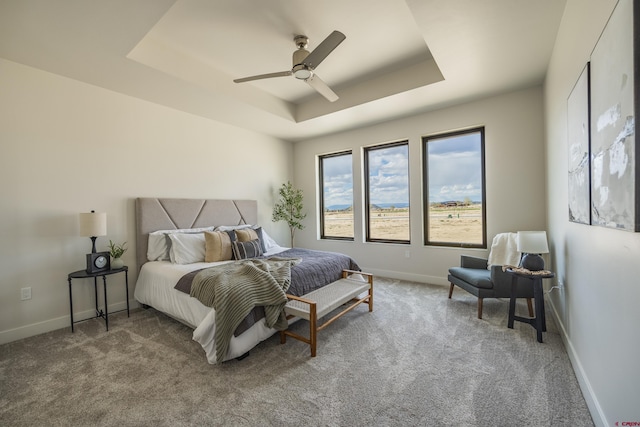 bedroom with a raised ceiling, carpet, and ceiling fan