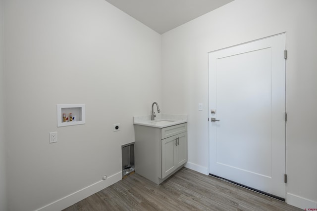 washroom featuring sink, cabinets, washer hookup, hookup for an electric dryer, and light hardwood / wood-style flooring