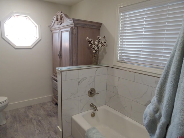 bathroom with a washtub, hardwood / wood-style floors, and toilet