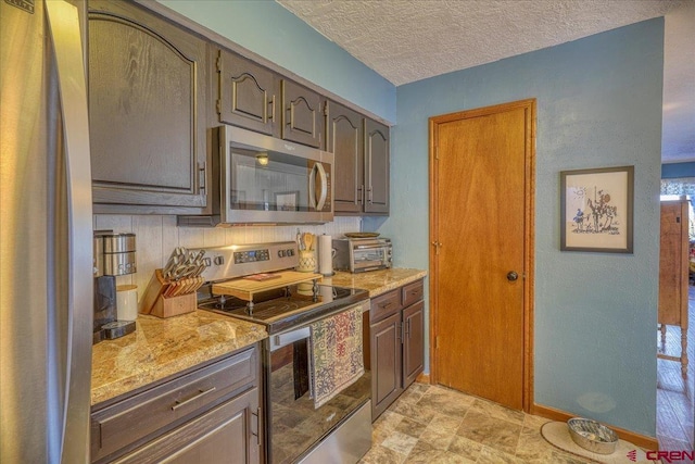 kitchen with light stone counters, stainless steel appliances, and a textured ceiling