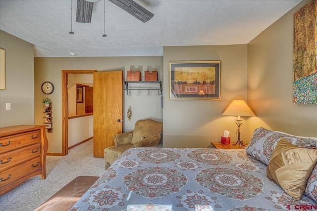 bedroom featuring a textured ceiling, light colored carpet, and ceiling fan