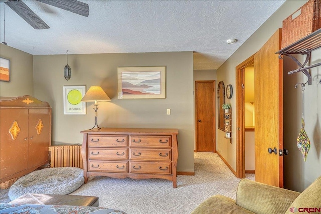 sitting room with ceiling fan, light carpet, and a textured ceiling