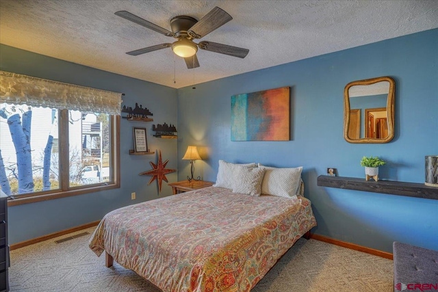 bedroom with ceiling fan, light colored carpet, and a textured ceiling