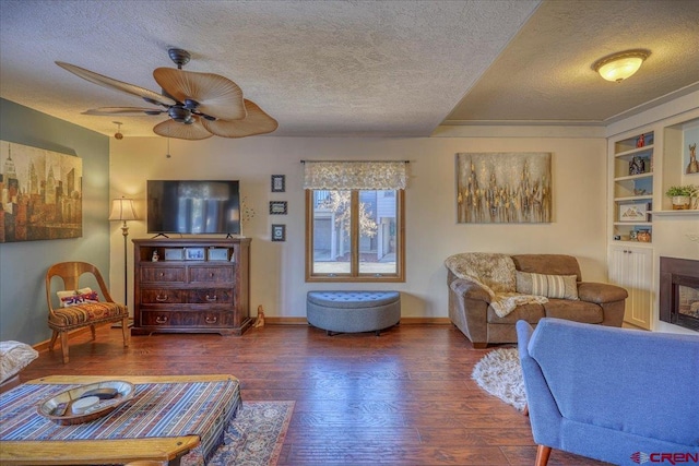 living room with dark hardwood / wood-style flooring, ceiling fan, built in features, and a textured ceiling