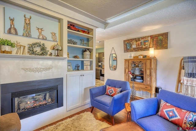 sitting room with light hardwood / wood-style floors, a textured ceiling, and built in shelves