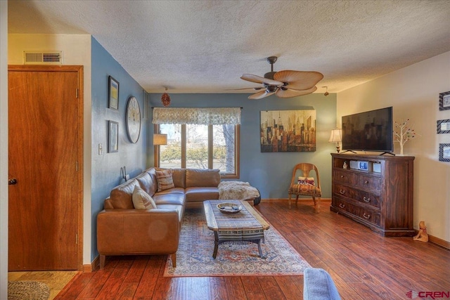 living room featuring ceiling fan, hardwood / wood-style floors, and a textured ceiling