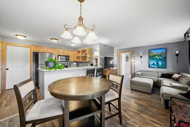 dining area featuring dark wood-type flooring and an inviting chandelier