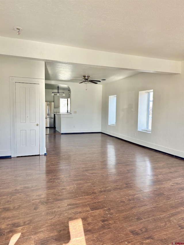 unfurnished living room featuring ceiling fan, dark hardwood / wood-style floors, and a wealth of natural light