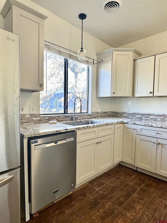 kitchen featuring sink, hanging light fixtures, stainless steel appliances, light stone counters, and white cabinets