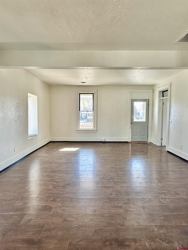 empty room with dark hardwood / wood-style floors and a textured ceiling