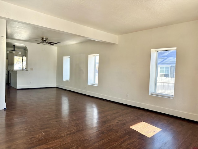 spare room with ceiling fan, dark hardwood / wood-style floors, and beam ceiling