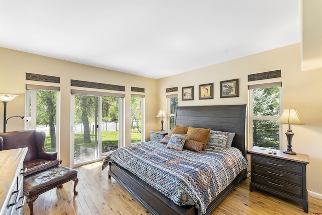 bedroom with multiple windows, access to exterior, and light hardwood / wood-style floors