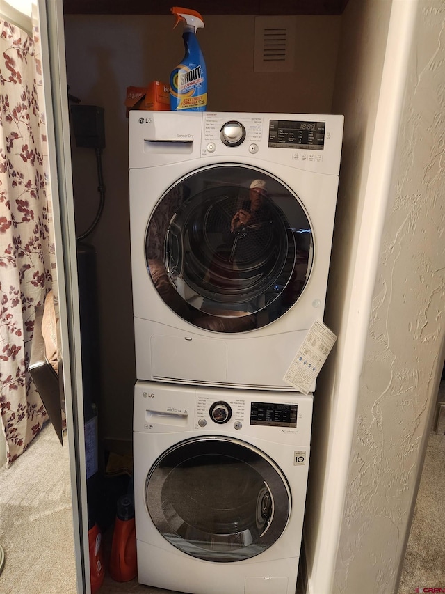 laundry room featuring stacked washing maching and dryer and carpet floors