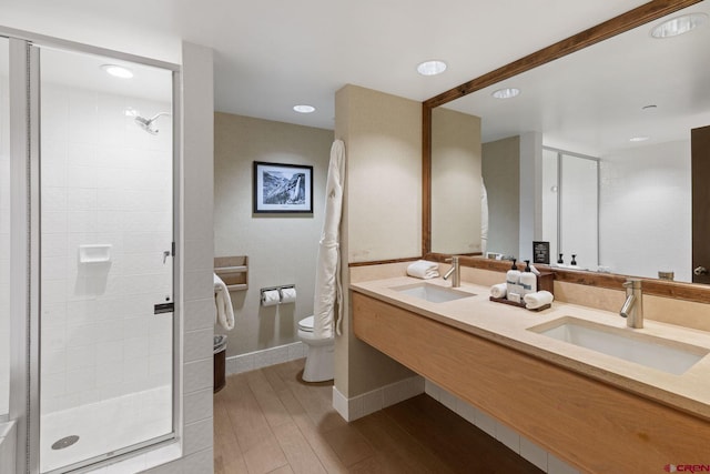 bathroom featuring a shower with door, vanity, and toilet