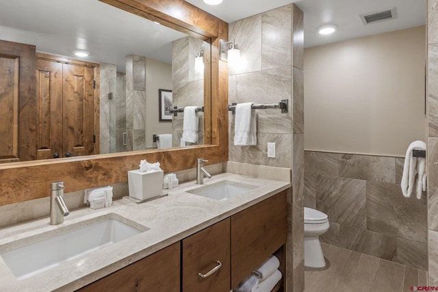 bathroom featuring vanity, tile walls, and toilet