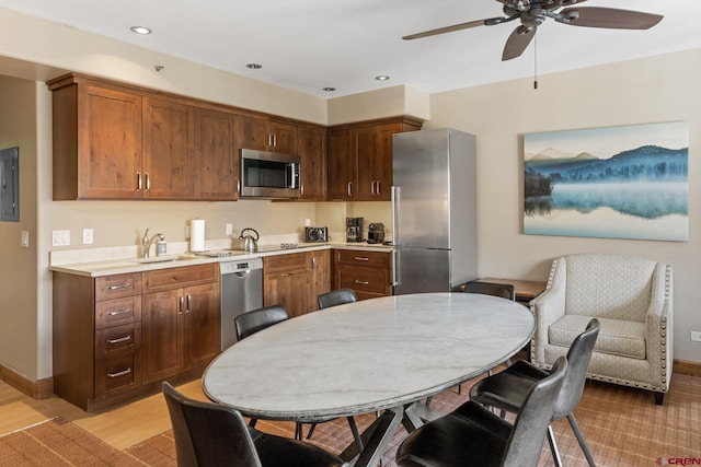 kitchen with sink, electric panel, ceiling fan, stainless steel appliances, and light wood-type flooring