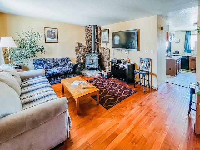 living room featuring light hardwood / wood-style flooring, a textured ceiling, and a wood stove