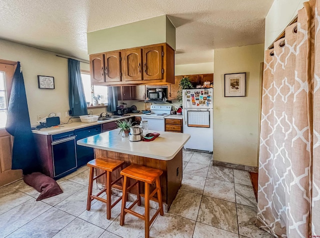 kitchen featuring a center island, a breakfast bar area, a textured ceiling, and white appliances