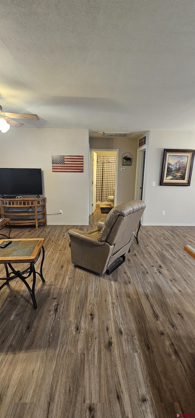 living room with ceiling fan, wood-type flooring, and a textured ceiling