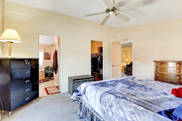 carpeted bedroom featuring a walk in closet, a closet, ceiling fan, and ensuite bathroom