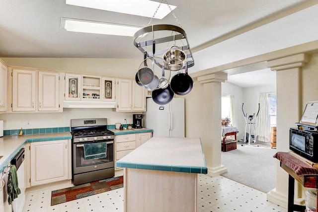 kitchen with ornate columns, a kitchen island, lofted ceiling, white refrigerator, and stainless steel gas range oven