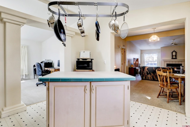 kitchen featuring pendant lighting, a center island, light carpet, and ceiling fan