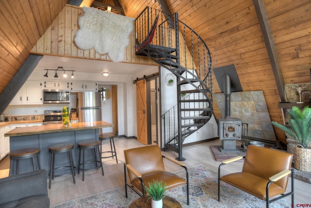 living room with wood ceiling, high vaulted ceiling, track lighting, light hardwood / wood-style floors, and a barn door