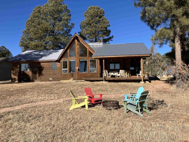 rear view of house with a wooden deck and a fire pit