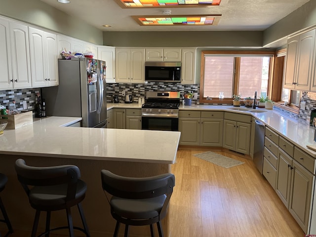 kitchen featuring sink, a breakfast bar, kitchen peninsula, and appliances with stainless steel finishes