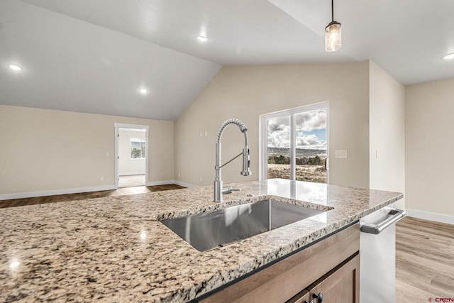 kitchen with pendant lighting, plenty of natural light, light stone countertops, and sink