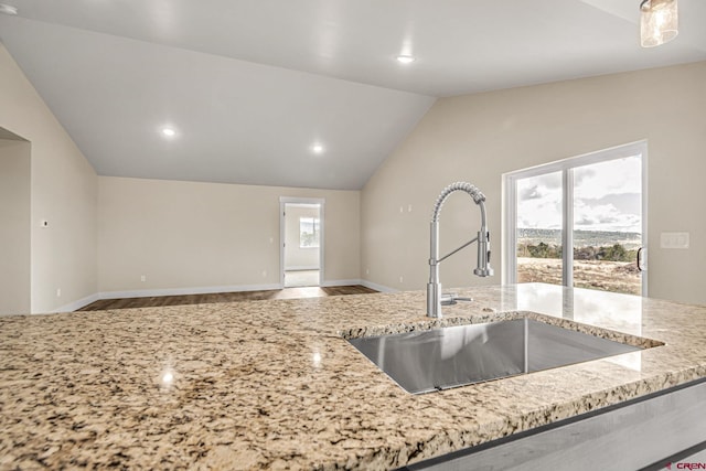 kitchen featuring lofted ceiling, sink, and light stone counters