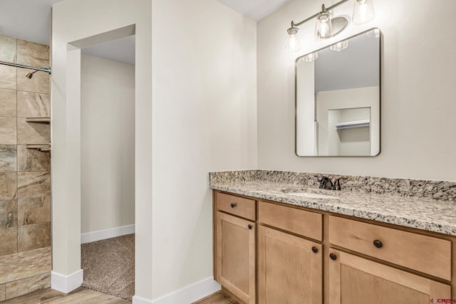 bathroom featuring vanity, hardwood / wood-style flooring, and a tile shower