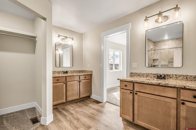 bathroom featuring hardwood / wood-style flooring, vanity, and a shower