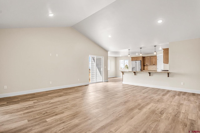 unfurnished living room featuring vaulted ceiling and light hardwood / wood-style flooring