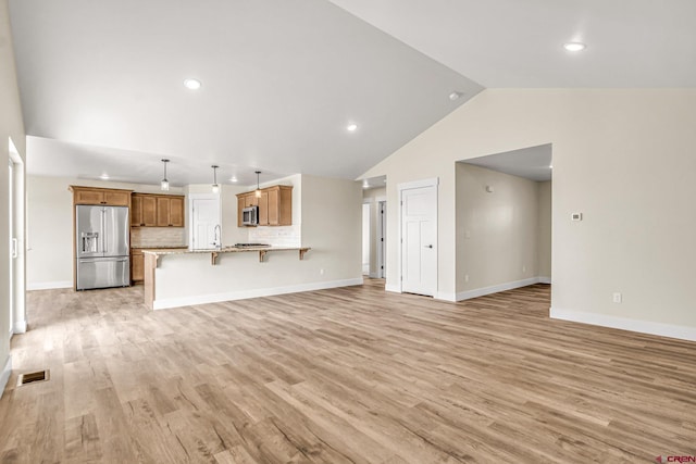 unfurnished living room featuring sink, high vaulted ceiling, and light wood-type flooring