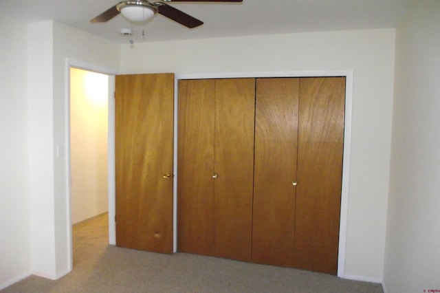 unfurnished bedroom featuring light colored carpet, ceiling fan, and a closet