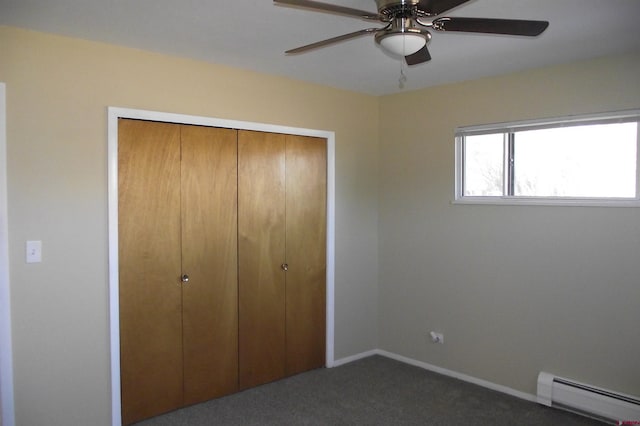 unfurnished bedroom with dark colored carpet, ceiling fan, a closet, and a baseboard heating unit