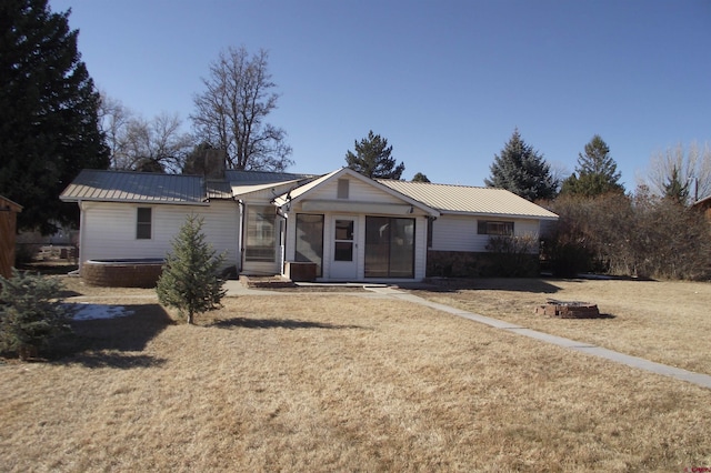 ranch-style house with a sunroom, a front yard, and an outdoor fire pit