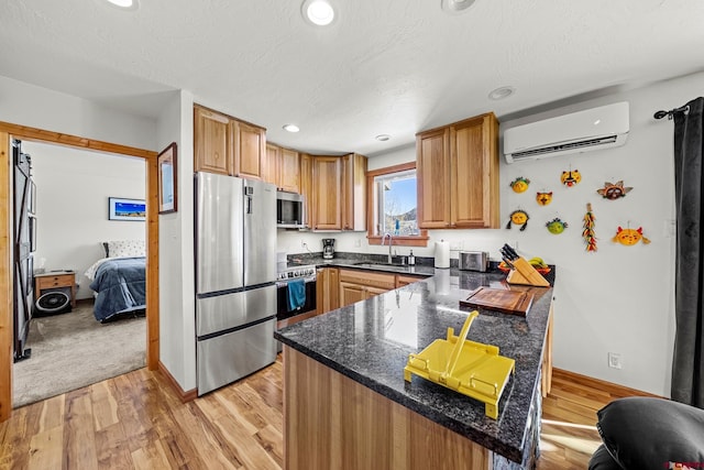 kitchen with stainless steel appliances, sink, a wall unit AC, and kitchen peninsula