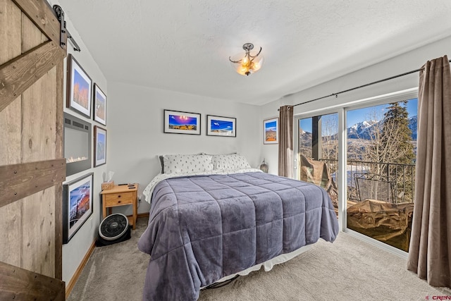 carpeted bedroom with access to exterior, a barn door, and a textured ceiling