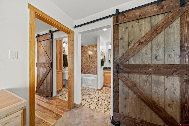 hallway featuring a barn door and light wood-type flooring