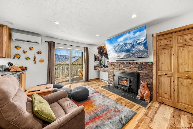 living room featuring a textured ceiling, a wall unit AC, and light hardwood / wood-style flooring