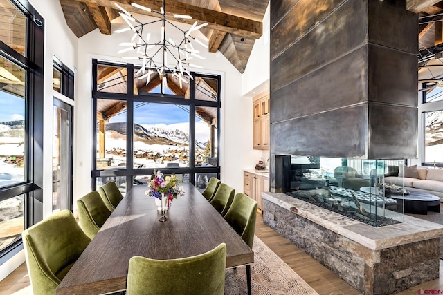 dining area with an inviting chandelier, high vaulted ceiling, light wood-type flooring, a mountain view, and beam ceiling