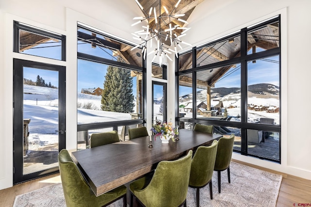 dining area with lofted ceiling, hardwood / wood-style floors, a mountain view, and a healthy amount of sunlight