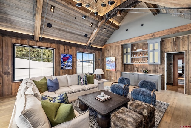 living room featuring beam ceiling, light wood-type flooring, and wooden walls