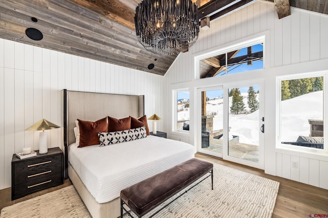 bedroom featuring light hardwood / wood-style flooring, access to exterior, a notable chandelier, and vaulted ceiling